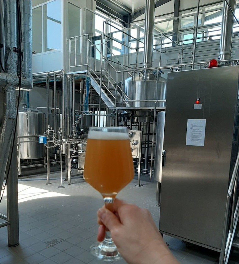 glass with beer in the background of beer tanks at Cretan Brewery plant